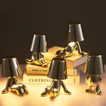Designerska lampa stołowa LED — figurka w pozycji siedzącej, połyskujące wykończenie | Norivo Norivo