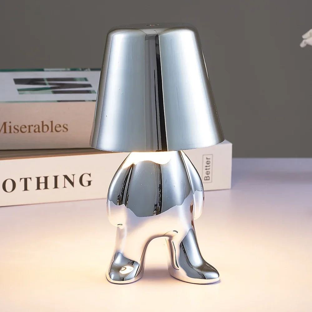 Designerska lampa stołowa LED — figurka w pozycji siedzącej, połyskujące wykończenie | Norivo Norivo
