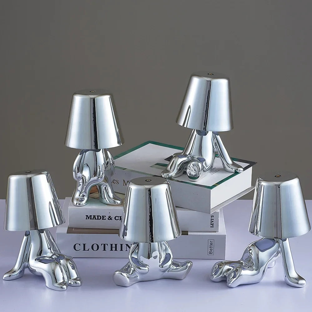 Designerska lampa stołowa LED — figurka w pozycji siedzącej, połyskujące wykończenie | Norivo Norivo