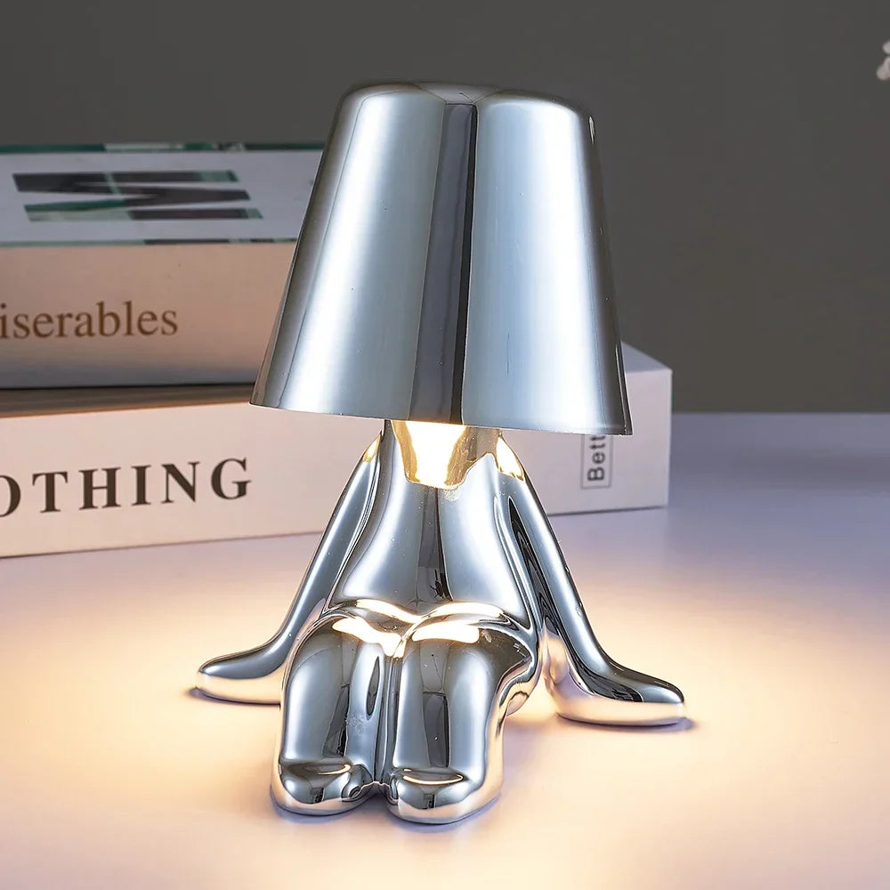 Designerska lampa stołowa LED — figurka w pozycji siedzącej, połyskujące wykończenie | Norivo Norivo
