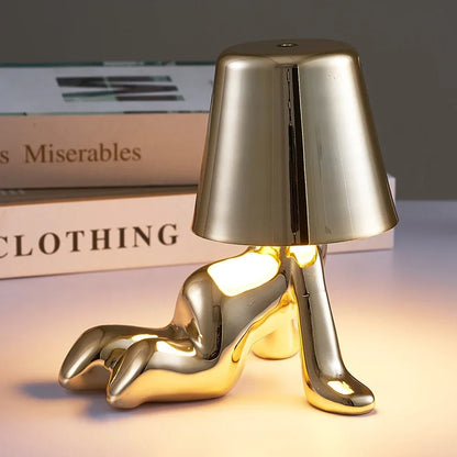 Designerska lampa stołowa LED — figurka w pozycji siedzącej, połyskujące wykończenie | Norivo Norivo